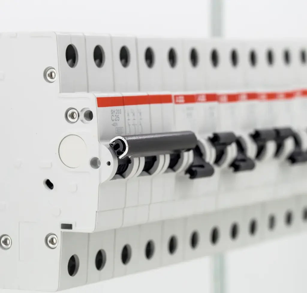 Close-up of a row of DIN-rail miniature circuit breakers, white with red bands, on a white background