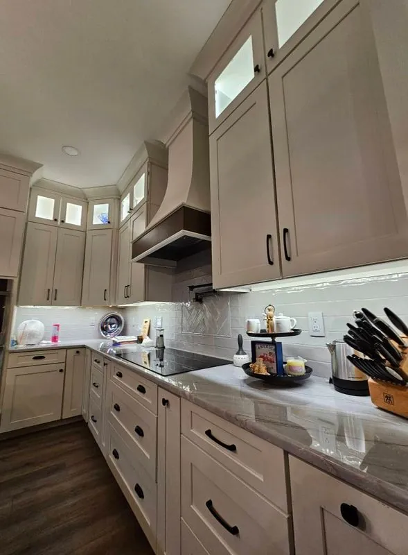White kitchen cabinets with under-cabinet lighting, tile backsplash and knife block